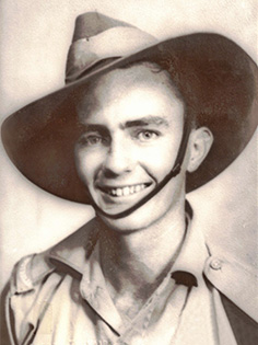 A smiling man in a military uniform and wide-brimmed hat poses for a portrait. The photograph is in black and white, giving it a vintage appearance.