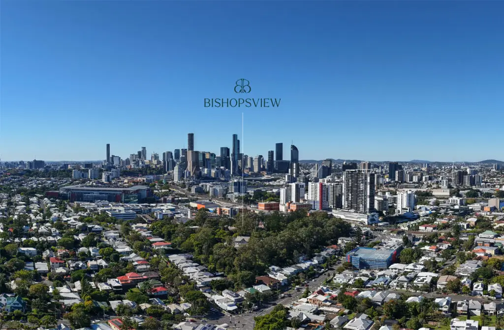 A panoramic view of a city skyline with tall buildings in the distance, residential houses and tree-lined streets, including the Milton retirement community, under a clear blue sky. The word "BISHOPSVIEW" is centered at the top.